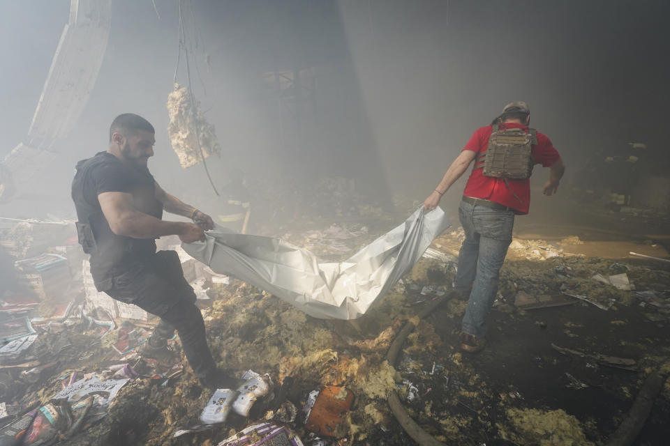 Rescuers carry a body after a Russian missile hit a large printing house in Kharkiv, Ukraine, Thursday, May 23, 2024. Russian missiles slammed into Ukraine’s second-largest city in the northeast of the country and killed at least seven civilians early Thursday, officials said, as Kyiv’s army labored to hold off an intense cross-border offensive by the Kremlin’s larger and better-equipped forces. (AP Photo/Andrii Marienko)