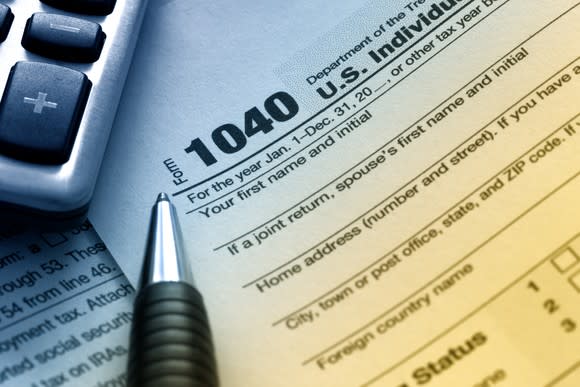 An IRS 1040 tax form next to a pen and calculator.