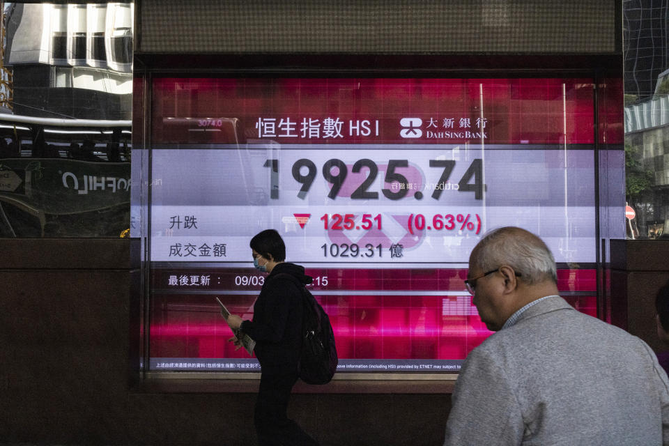 People walk by the Dah Sing Bank's electronic screen in Hong Kong on Friday, March 10, 2023. Asian stock markets followed Wall Street lower Friday ahead of an update on U.S. employment amid worries about possible further interest rate hikes. (AP Photo/Louise Delmotte)