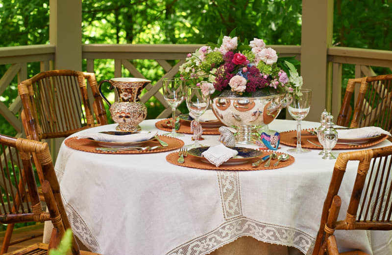 Floral arrangement in silver urn on summer decorated outdoor table.