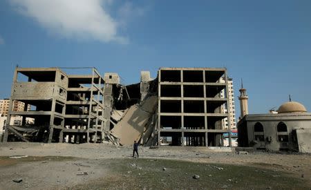 A Palestinian passes a building that was destroyed by Israeli air strikes in Gaza City July 15, 2018. REUTERS/Suhaib Salem