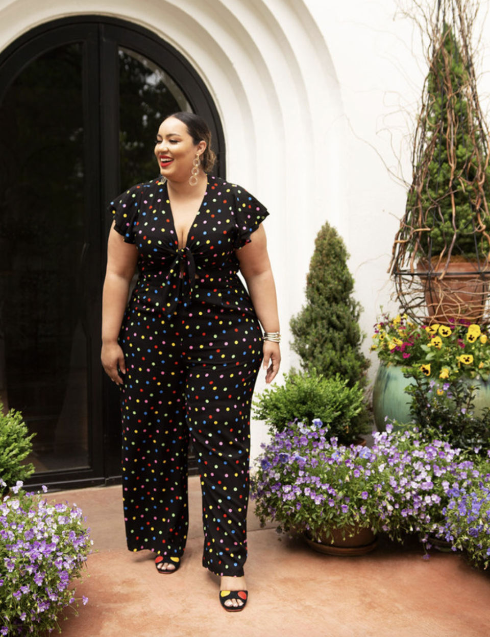 plus size model walking in v-neck polka dot jumpsuit and black heels