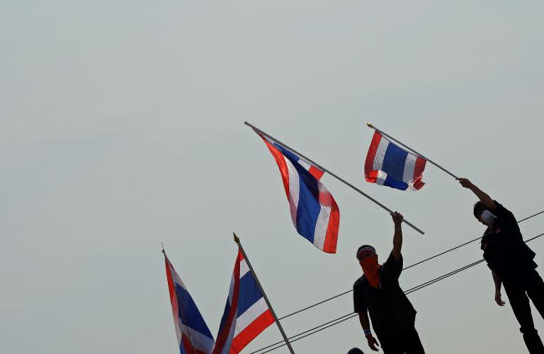 Thai anti-government protesters wave national flags after removing concrete barricades at the Government House in Bangkok, on December 3, 2013