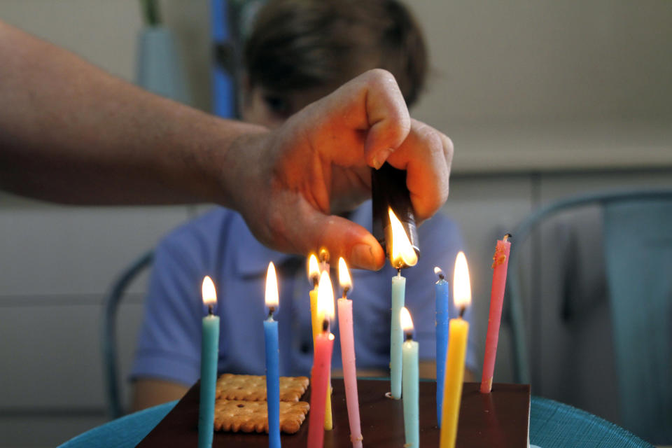 parent lighting birthday candles in front of a child