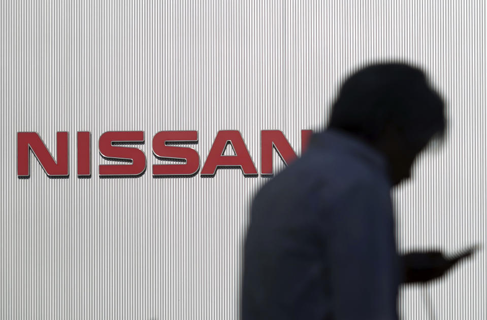 In this Nov. 21, 2018, photo, a man walks near the logo of Nissan Motor Co. at its Global Headquarters in Yokohama, near Tokyo. Japanese media say Tokyo prosecutors charged Nissan former chairman Carlos Ghosn on Monday, Dec. 10, 2018, with underreporting his income by 5 billion yen ($44 million) over five years, with another executive and the company. (AP Photo/Eugene Hoshiko)