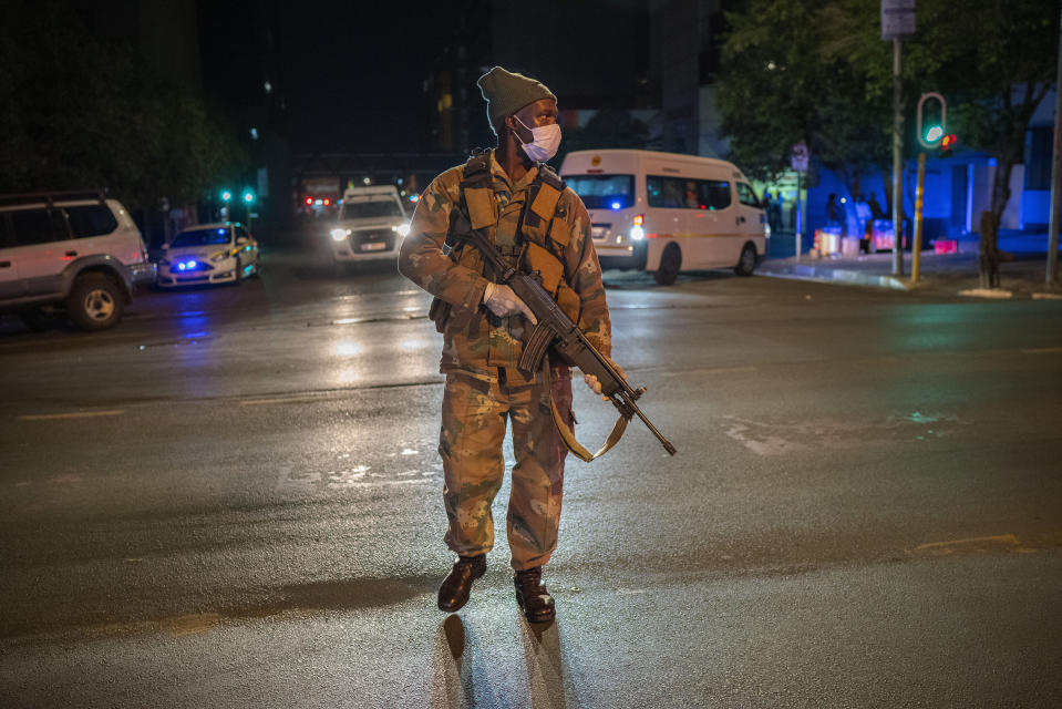 A South African soldier enforces the lockdown downtown Johannesburg, South Africa, Friday, March 27, 2020. Police and army started patrolling moments after South Africa went into a nationwide lockdown for three weeks in an effort to mitigate the spread to the coronavirus. The new coronavirus causes mild or moderate symptoms for most people, but for some, especially older adults and people with existing health problems, it can cause more severe illness or death.(AP Photo/Jerome Delay)