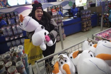 A girl poses with an Olaf plush toy from Disney's Frozen toy line at the Toys R Us store in Times Square in New York November 27, 2014. REUTERS/Carlo Allegri