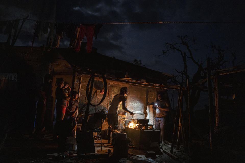 The Ramos family cooks dinner over a fire outside their storm-damaged home that continues without electricity one week after Hurricane Ian in La Coloma, Pinar del Rio province, Cuba, Wednesday, Oct. 5, 2022. (AP Photo/Ramon Espinosa)