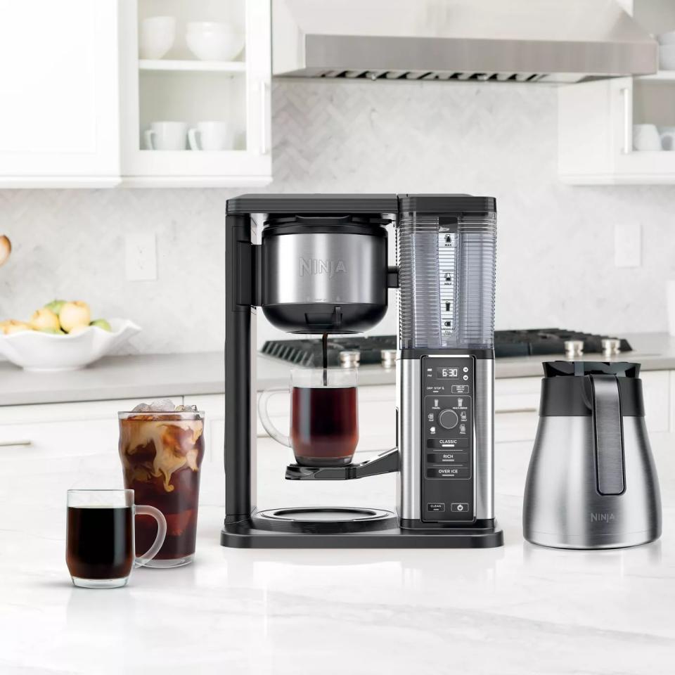 the black coffee maker on a counter preparing a cup of coffee