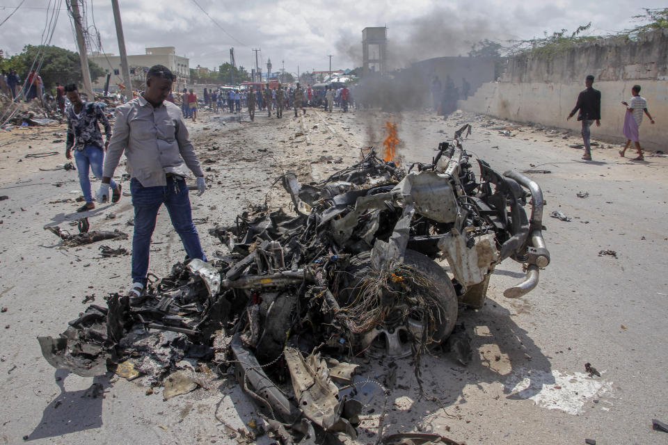 Security forces and civilians gather near the wreckage after a suicide car bomb attack that targeted the city's police commissioner in Mogadishu, Somalia Saturday, July 10, 2021. At least nine people are dead and others wounded after the large explosion, a health official at the Medina hospital said, noting that the toll reflected only the dead and wounded brought there. (AP Photo/Farah Abdi Warsameh)