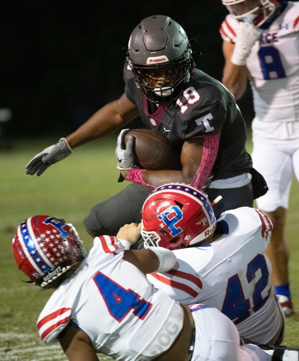 Tate's Andre Colston (No. 18) tries his best to bulldozer his way through the Pace defense during Friday night's district matchup.