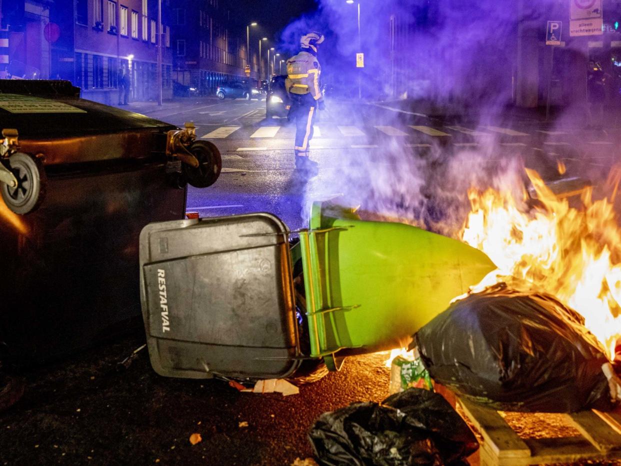 A view of a burning dumpster and other waste containers as a police officer keeps watch in the Schilderswijk neighborhood in The Hague, the Netherlands: EPA