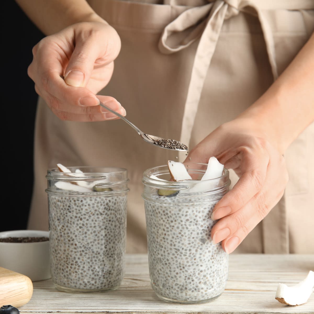 woman sprinkling chia seeds on chia seed pudding