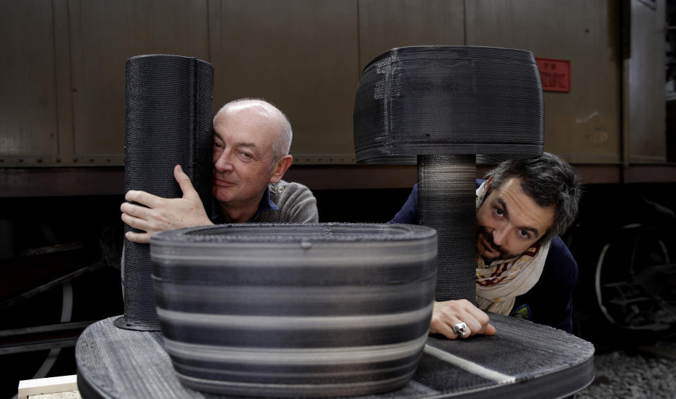 In this picture taken on Friday, April 12, 2019, from left, designers Piero and Francesco Lissoni pose next to their creation set consisting of a set of bowl, a vase and a lamp, made with upcycled plastic, at the National Museum of Science and Technology, during the "RO Plastic - Master's Pieces" exhibition', on the sidelines of the Salone del Mobile International Furniture Fair week, in Milan, Italy. Scientists and environmental activists have been long raised the alarm on plastic pollution. Now, the high-end design world is getting in on the growing global effort to tackle plastic pollution -- by upcycling discarded objects into desirable one-off design pieces. (AP Photo/Luca Bruno)