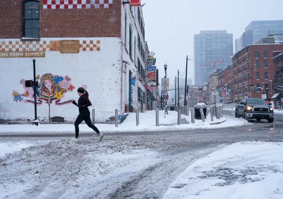A jogger maneuvers through the freshly fallen snow on S. 1st Avenue in Nashville, Tenn., Monday, Jan. 15, 2024.