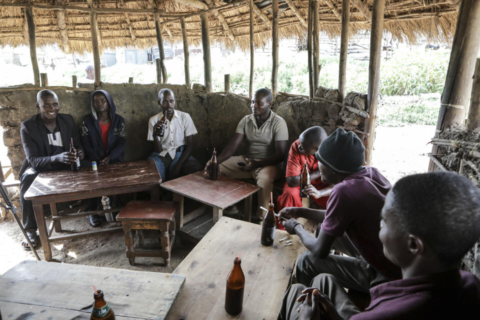 Local patrons share tonto at a local bar in Majengo village, Mbarara, Uganda, Dec. 10, 2023. Tonto is a legendary traditional drink in Uganda. But the fermented banana juice is under threat as authorities move to regulate the production of what are considered illicit home brews. (AP Photo/Hajarah Nalwadda)