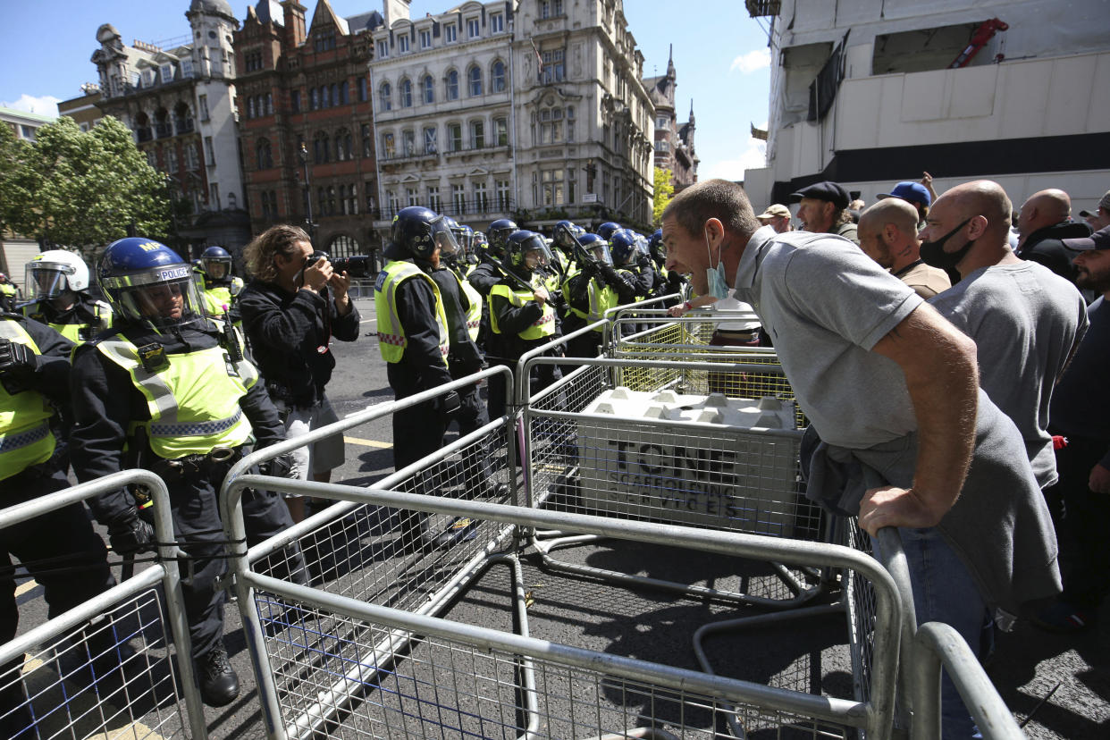 Police are confronted by protesters in Whitehall near Parliament Square, London, during a protest by the Democratic Football Lads Alliance against a Black Lives Matter protest, Saturday June 13, 2020.  The death of George Floyd in the United States, has prompted demonstrations by far-right groups as well as the Black Lives Matter movement and provoked a wider debate regarding many historical figures and Britain's colonial past. (Jonathan Brady/PA via AP)