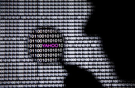 A photo illustration shows a man in front of a Yahoo logo seen through a magnifying glass in front of a displayed cyber code on December 16, 2016. REUTERS/Dado Ruvic/File Photo