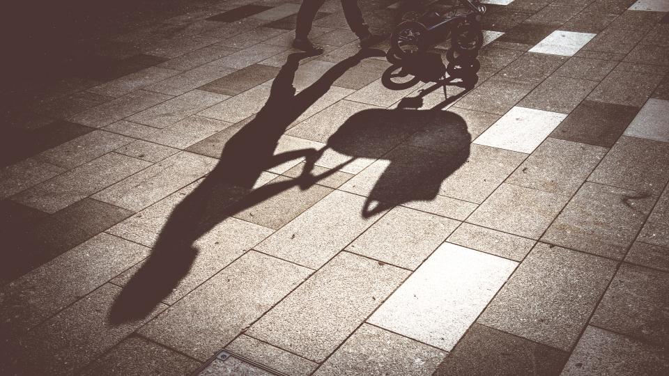 Close-up of a woman driving a baby carriage in the city, gray stone as background, Slovenia, Europe. Nikon D850.