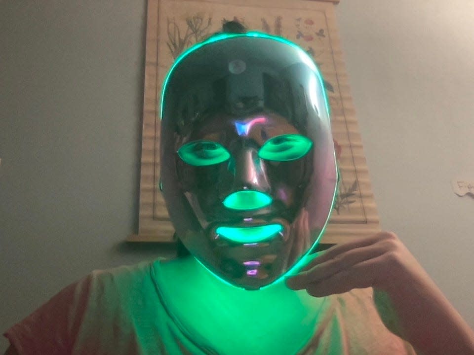 A person wearing a shiny LED face mask lit with green lights.