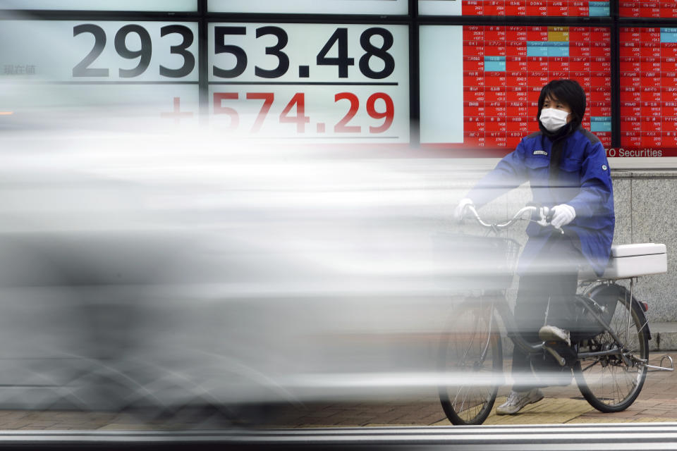 A woman wearing a protective mask rides a bicycle in front of an electronic stock board showing Japan's Nikkei 225 index at a securities firm Monday, Feb. 8, 2021, in Tokyo. Asian shares mostly rose Monday, tracking a rally on Wall Street last week, with Japan's benchmark momentarily reaching three-decade highs, on growing optimism about the global economy. (AP Photo/Eugene Hoshiko)