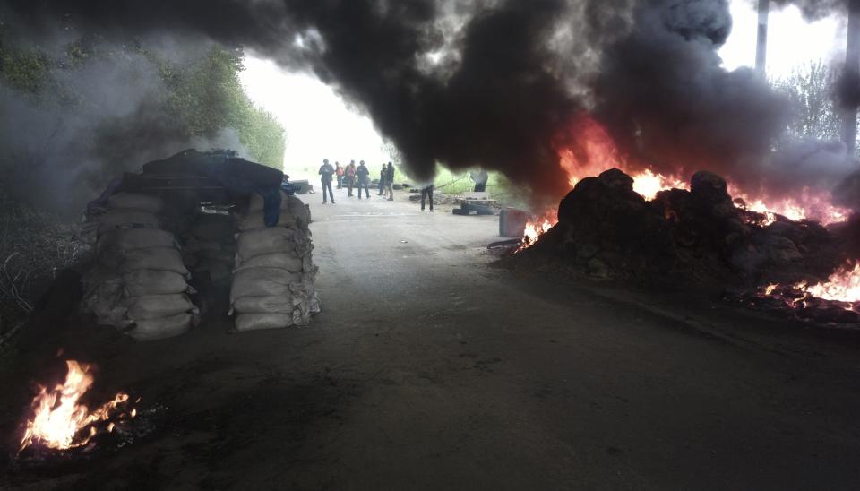 A group of journalists look at burning tires at a checkpoint following an attack by Ukrainian troops outside in Slovyansk, Ukraine, Thursday, April 24, 2014. Ukrainian government troops moved against pro-Russia forces in the east of the country on Thursday and killed at least two of them in clashes at checkpoints manned by the insurgents, the government and insurgents said. Russian President Vladimir Putin decried what he described as a "punitive operation." (AP Photo/Mika Velikovskiy)