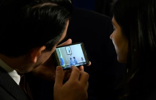 At a gathering of the Organization of American States (OAS) in Washington, two people watch a phone showing a speech by Brazil's culture secretary Roberto Alvim in which he was accused of quoting Joseph Goebbels