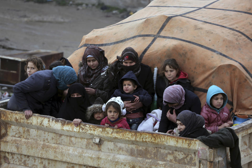 Syrians sit in the back of a truck as they flee the advance of the government forces in the province of Idlib, Syria, towards the Turkish border, Thursday, Jan. 30, 2020. Warplanes struck a town in a rebel-held enclave in northwestern Syria, killing several people, including some who were fleeing the attack, opposition activists and a rescue service said Thursday. The attack, believed to have been carried out by Russian warplanes backing a Syrian government offensive, also put a local hospital out of service, they said. (AP Photo/Ghaith Alsayed)