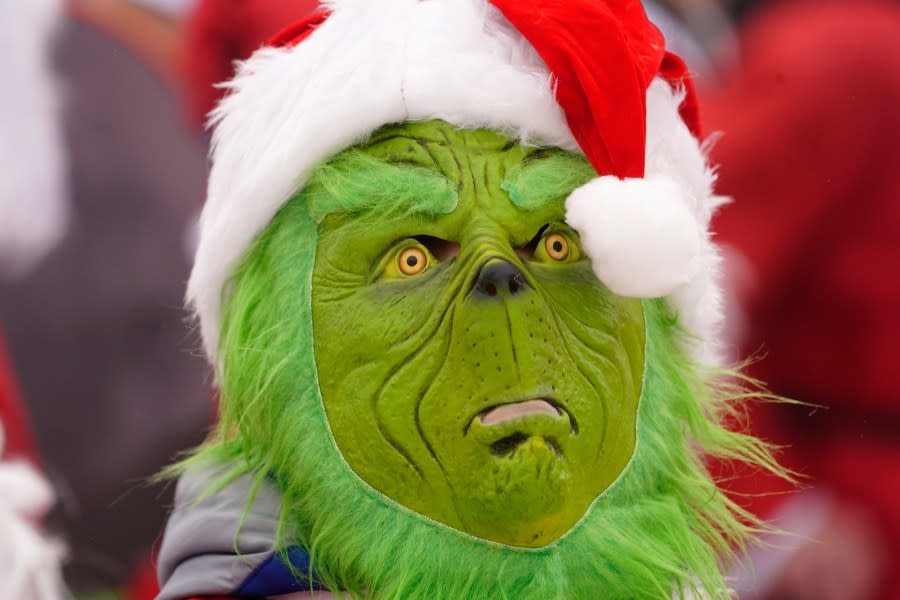 A skier wears a Grinch mask as he joins others dressed as Santa Claus, Sunday, Dec. 10, 2023, at the Sunday River Ski resort in Newry, Maine. The annual Santa Sunday event raises money for local charities. (AP Photo/Robert F. Bukaty)