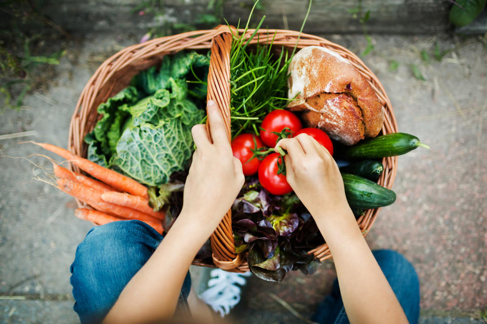 A woman holding a basket of fresh vegetables