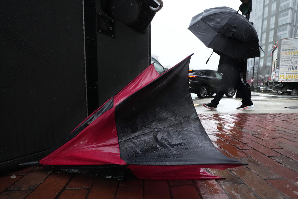 A commuter walks past a destroyed umbrella while heading towards South Station through wind-driven rain, Thursday, April 4, 2024, in Boston. (AP Photo/Charles Krupa)