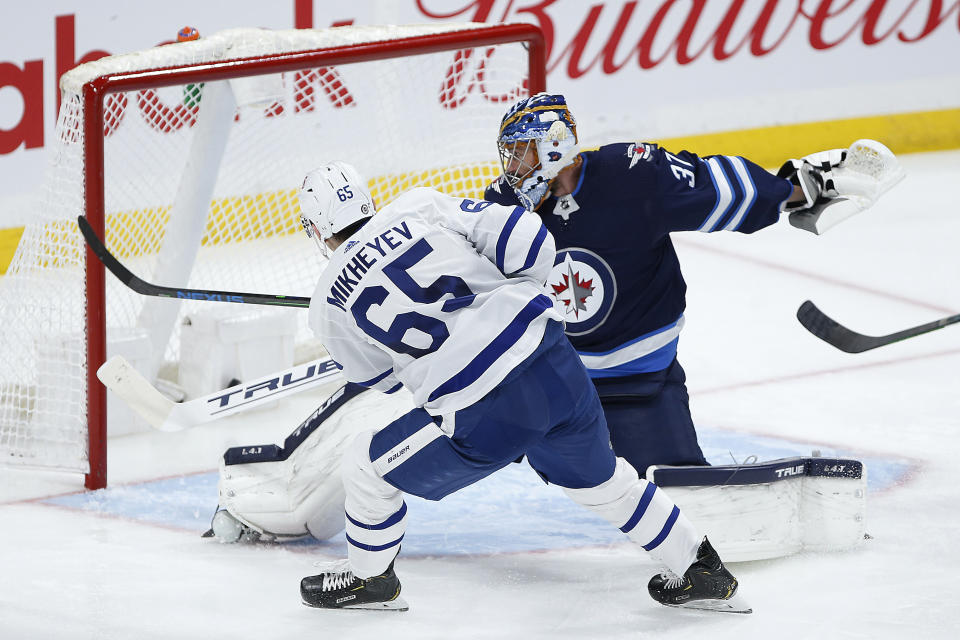 Toronto Maple Leafs' Ilya Mikheyev (65) scores on Winnipeg Jets goaltender Connor Hellebuyck (37) during the second period of an NHL hockey game Friday, May 14, 2021, in Winnipeg, Manitoba. (John Woods/The Canadian Press via AP)