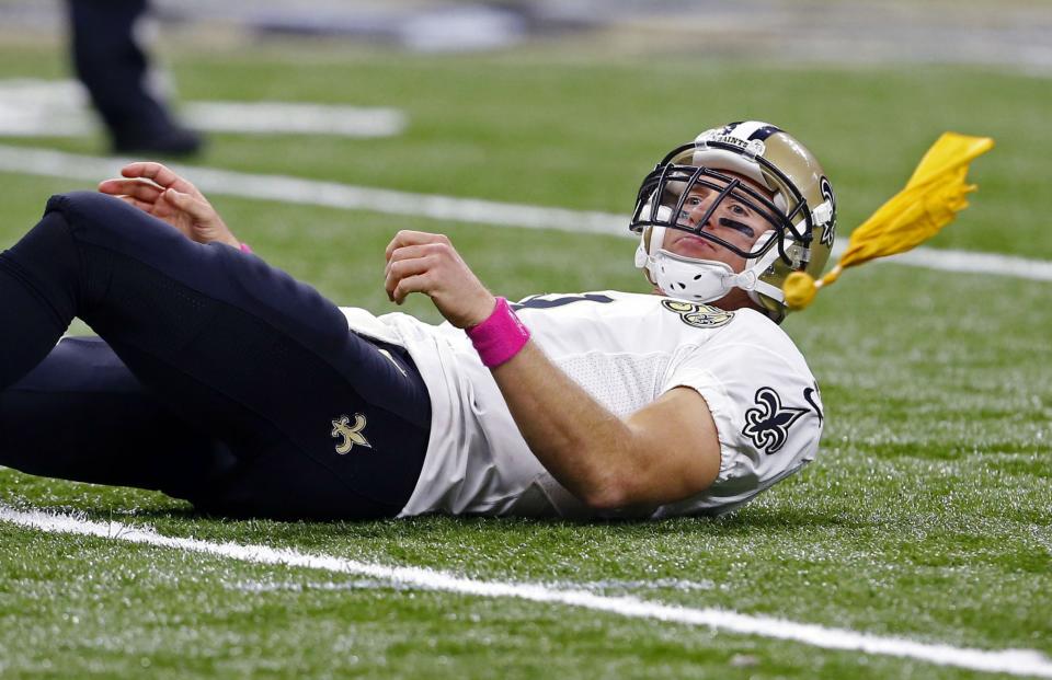 <p>New Orleans Saints quarterback Drew Brees (9) lies on the ground as a penalty flag is thrown, after he released a touchdown throw in the second half of an NFL football game in New Orleans, Sunday, Oct. 16, 2016. Carolina Panthers defensive tackle Kawann Short (99) was called for a personal foul on the play for shoving him down in the face. (AP Photo/Butch Dill) </p>