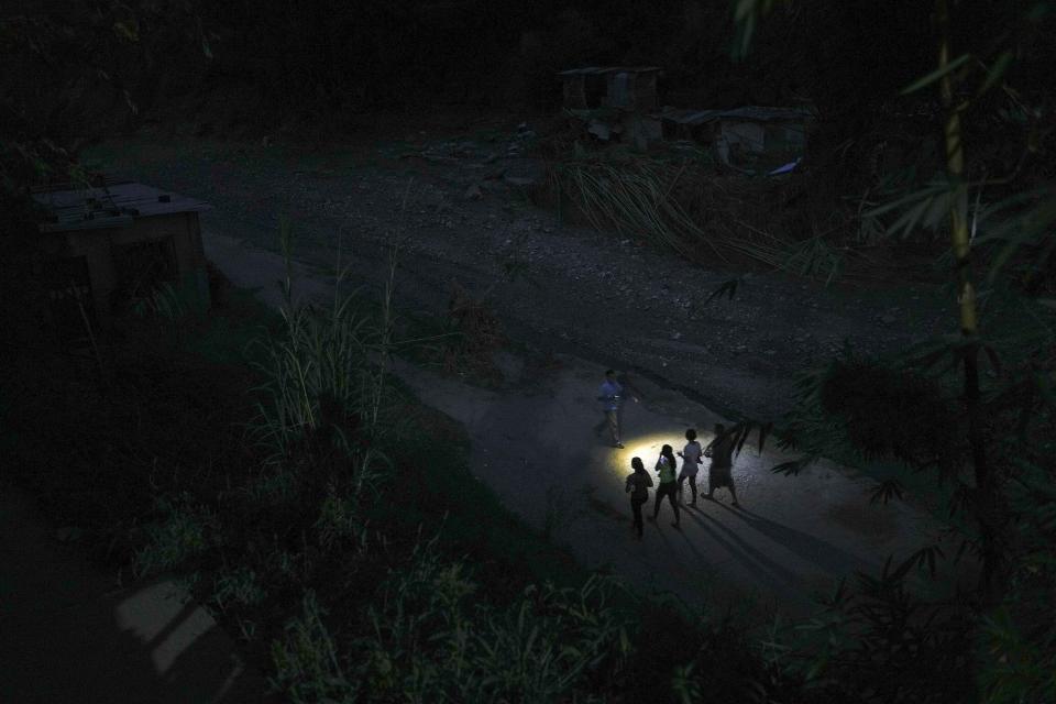 Residents walk where homes were washed away by a landslide in Las Tejerias, Venezuela, late Tuesday, Oct. 11, 2022. Three days after the massive and deadly landslide, rescuers expanded their search for any bodies buried under the sludge. (AP Photo/Matias Delacroix)