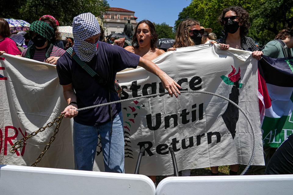 A demonstrator chains tables together to make a makeshift barrier around a protest encampment Monday on the UT South Mall.