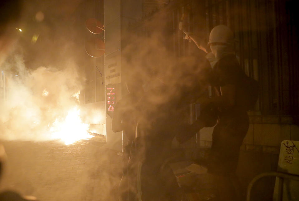 Protester react to tear gas as a fire burns on the streets of Hong Kong on Wednesday, Oct. 2, 2019. Protests continue a day after police shot a teenage demonstrator at close range during widespread anti-government demonstrations on China's National Day and marked a fearsome escalation in Hong Kong's protest violence. (AP Photo/Kin Cheung)