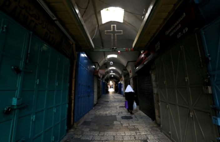 A woman walks past closed shops along a deserted alley in the Old City of Jerusalem (AFP Photo/Emmanuel DUNAND)
