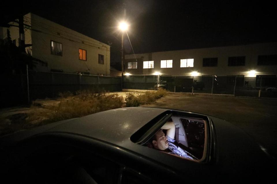 Saul watches news reports on his smart phone while parked in a Safe Parking lot where he spends the night in Hollywood.