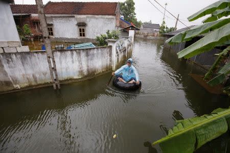 A man paddles an improvised boat along a flooded village after a heavy rain caused by a tropical depression in Hanoi, Vietnam October 16, 2017. REUTERS/Kham