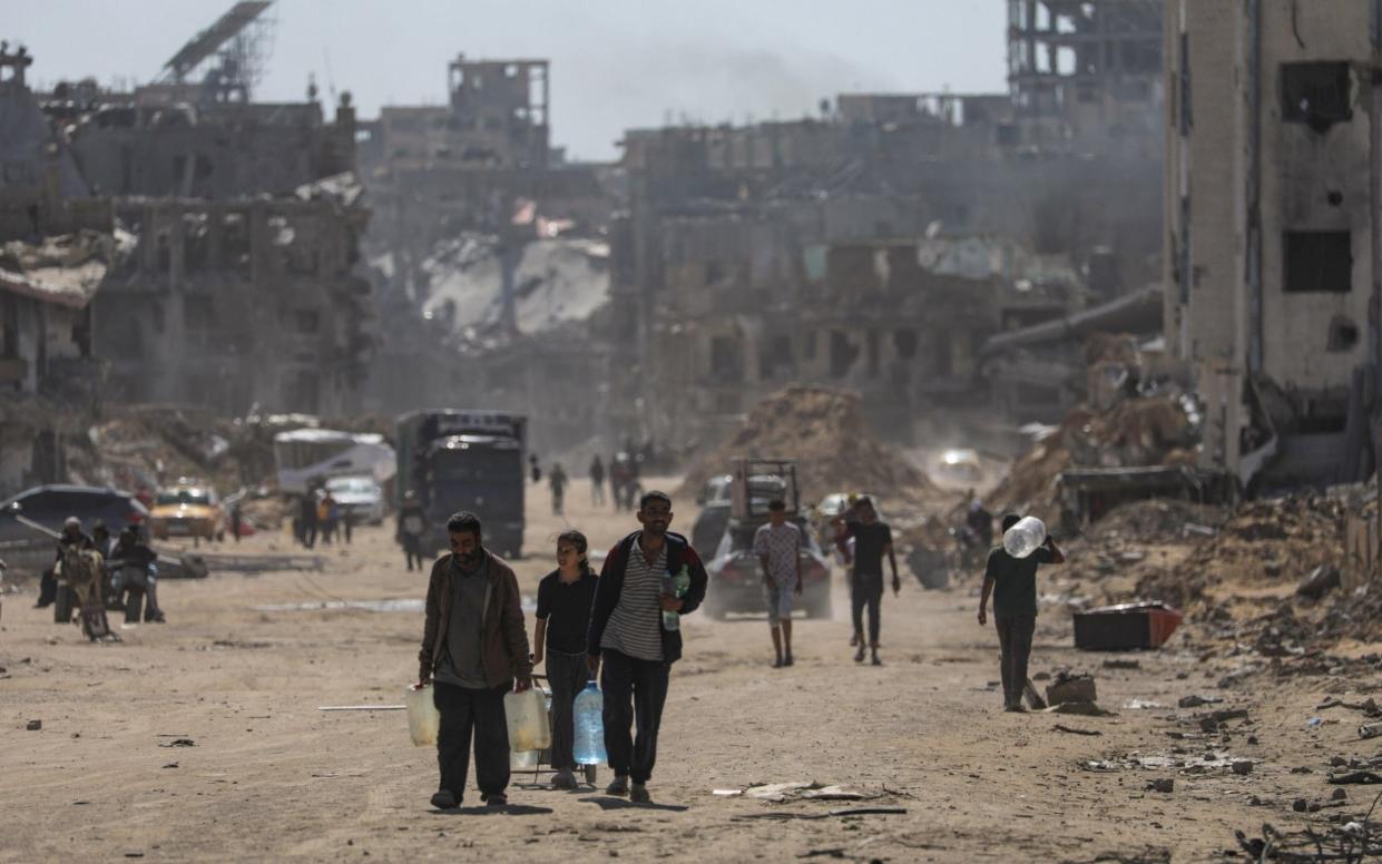 Palestinians walk after returning to Khan Younis town, southern Gaza Strip