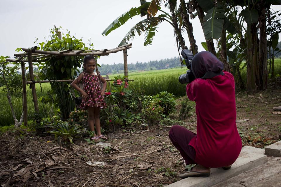 PURWOREJO, INDONESIA - MARCH 14: Armless professional photographer Rusidah, 44, takes a customer's portrait on March 14, 2012 in Purworejo, Indonesia. Rusidah shoots weddings and parties and has a small studio at home in the village of Botorejo, Bayan District, Purworejo, Central Java where her husband and son also reside. She has been in the photography business for nearly 20 years. (Photo by Ulet Ifansasti/Getty Images)