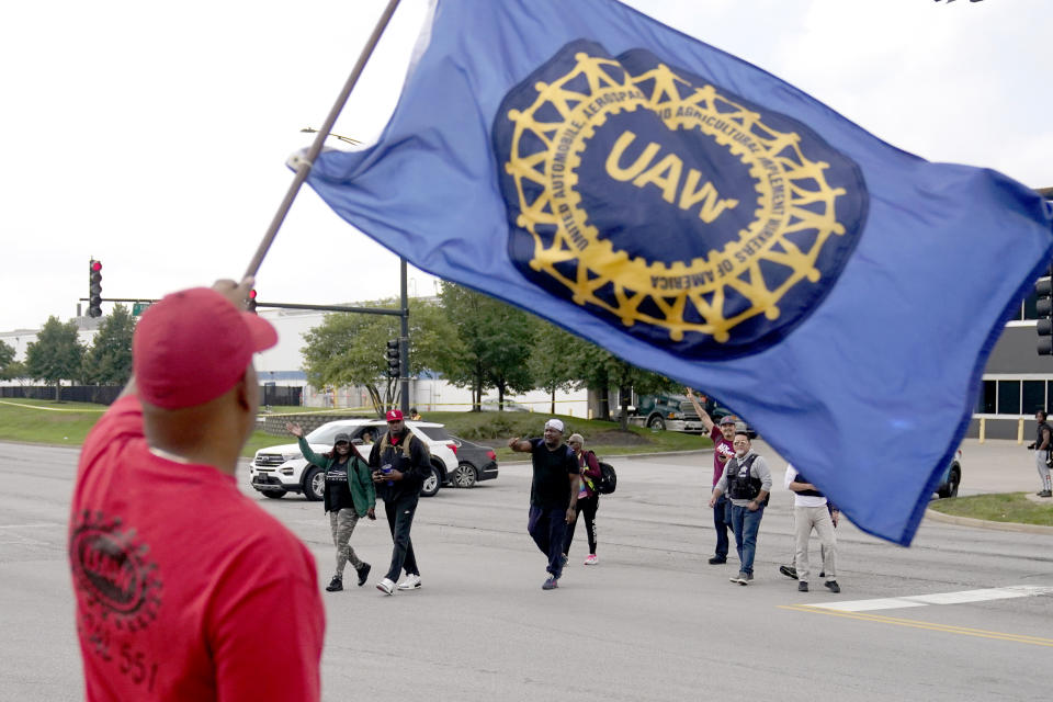 Members of the United Auto Worker Union walk out of the Chicago Ford Assembly Plant as Lance Williams from Lansing, Ill., waves the UAW flag Friday, Sept. 29, 2023, in Chicago. (AP Photo/Charles Rex Arbogast)