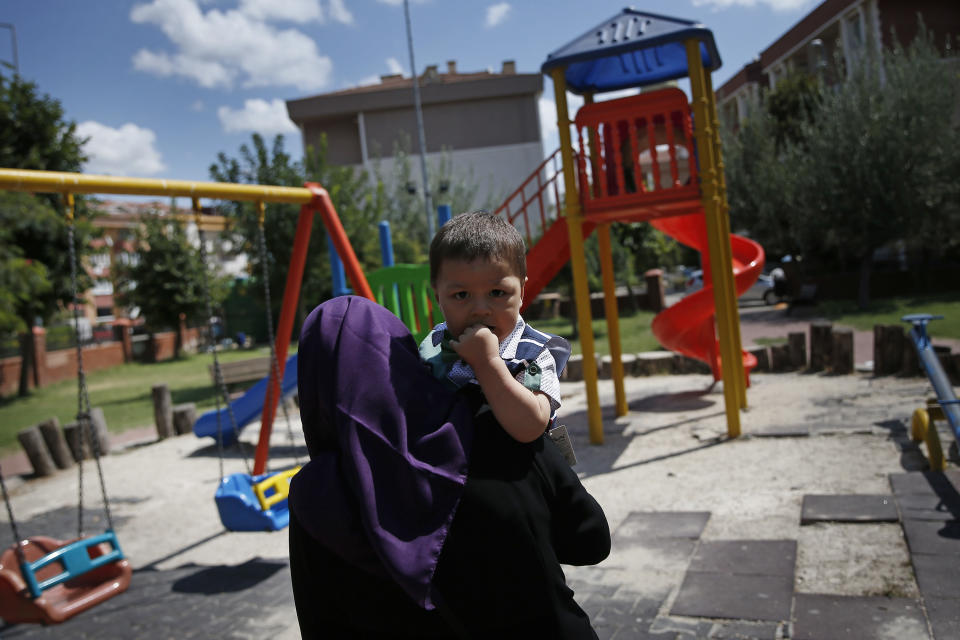 In this Aug. 21, 2018, photo, Meripet, 29, carries her son Abduweli, at a playground in Istanbul, Turkey. Meripet came to Turkey in February 2017 to visit her sick father, leaving four children behind. While in Turkey, she heard Uighur passports were being seized and that people who had gone abroad were being taken to reeducation – so she stayed in Turkey, giving birth to Abduweli. She hasn't seen her other four children since, and heard they were taken to a live-in kindergarten in Hotan, China. (AP Photo/Lefteris Pitarakis)