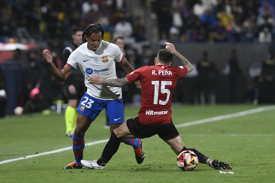 Barcelona's Jules Kounde, left, fights for the ball with Osasuna's Ruben Pena during the Spanish Super Cup semi final soccer match between Osasuna and Barcelona at Al Awal Park Stadium in Riyadh, Saudi Arabia, Thursday, Jan. 11, 2024. (AP Photo)