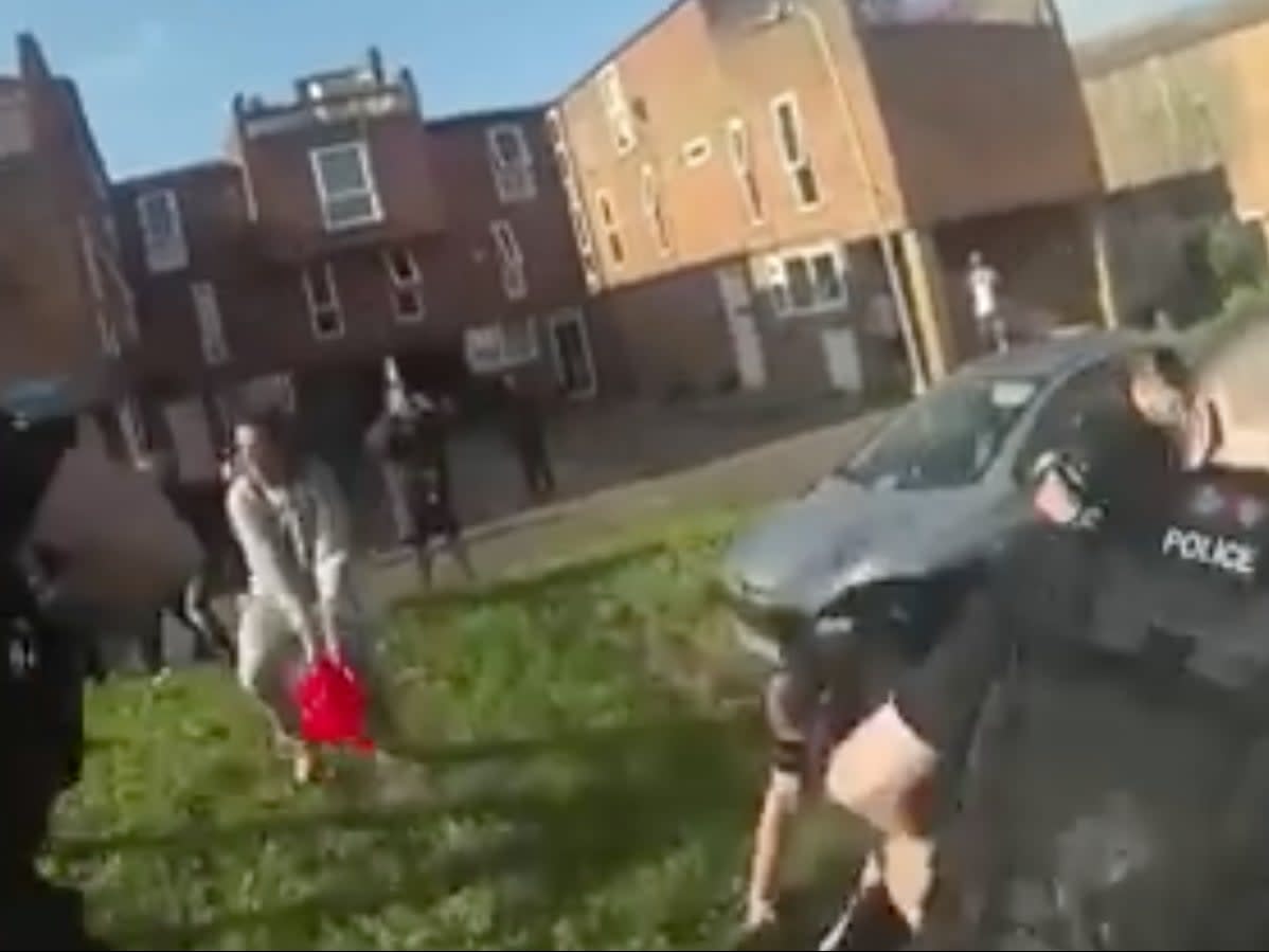 A still from video footage of the incident shows police ducking as Justin Jackson throws petrol at them out of a red watering can  (Facebook/ITV Anglia)