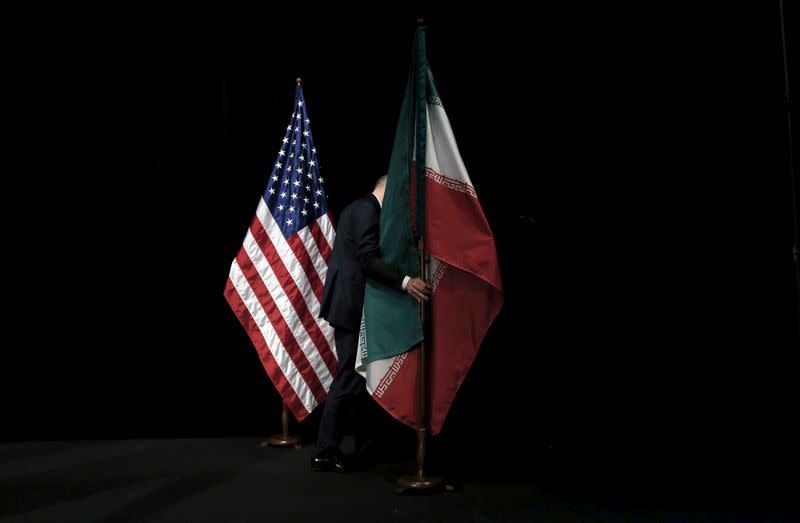 FILE PHOTO: A staff member removes the Iranian flag from the stage after a group picture with foreign ministers and representatives during the Iran nuclear talks at the Vienna International Center in Vienna