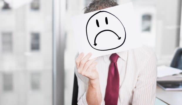 Businessman holding picture of sad face