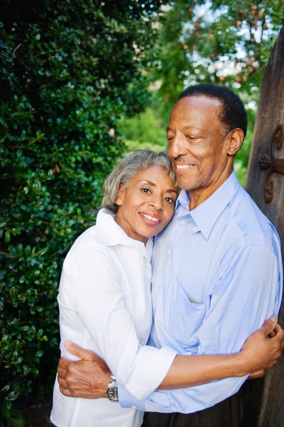 Alice and Ralph Evans embrace for a photo against a backdrop of trees.