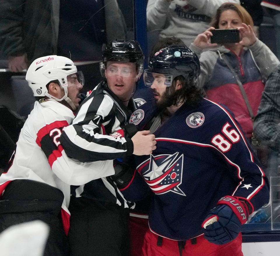 Dec. 1, 2023; Columbus, Ohio, USA; 
An official separates Ottawa Senators defenseman Travis Hamonic (23) and Columbus Blue Jackets left wing Kirill Marchenko (86) during the third period of Friday's hockey game at Nationwide Arena. The Jackets won the game 4-2.