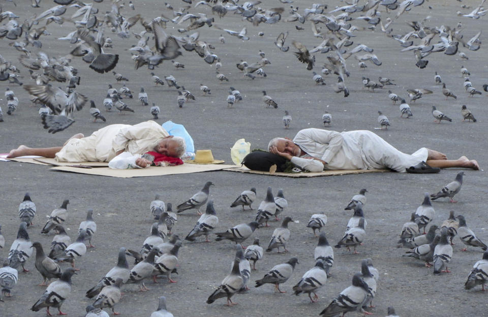 Pigeons surround pilgrims outside the the Grand Mosque in the Saudi Arabia's holy city of Mecca, Tuesday, July 5, 2022. Saudi Arabia is expected to receive one million Muslims to attend Hajj pilgrimage, which will begin on July 7, after two years of limiting the numbers because coronavirus pandemic. (AP Photo/Amr Nabil)